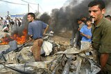 Palestinians crowd around wrecked car
