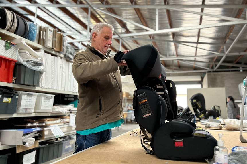 Anthony restoring a child's car seat in a warehouse