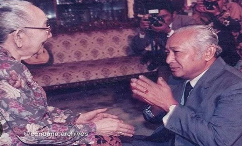 A black and white photo of Indonesia's second president Suharto bowing down and putting his hands together.