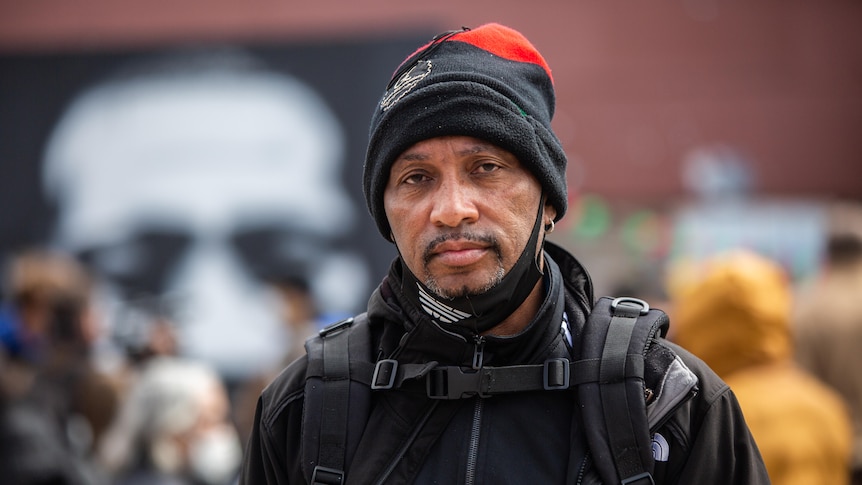 A man with a black beanie looks at the camera 