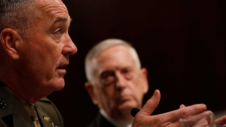 General Joseph Dunford speaks with Pentagon chief Jim Mattis in the background.