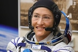 Christina Koch smiles while wearing her spacesuit, sans the helmet.