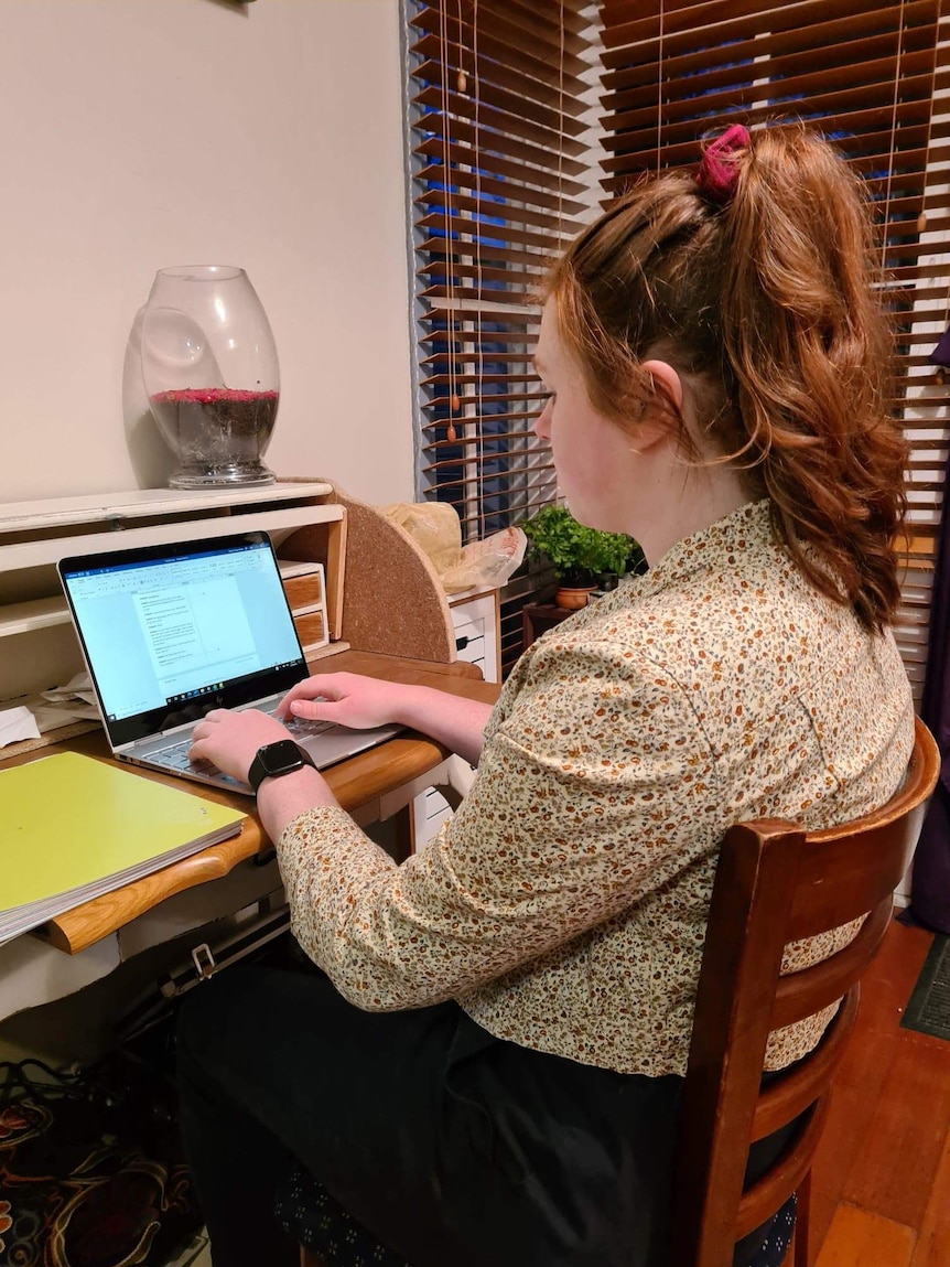 Bronte sits at a desk typing on laptop