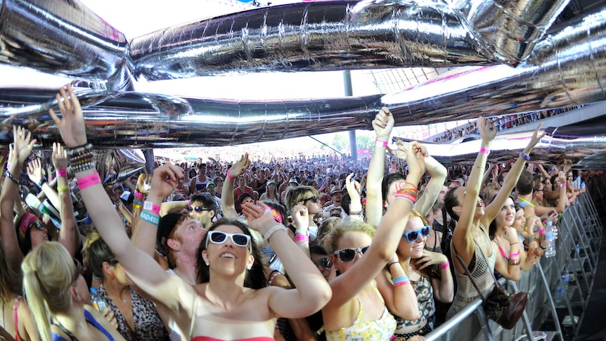 A crowd of festival goers with arms raised towards the stage.