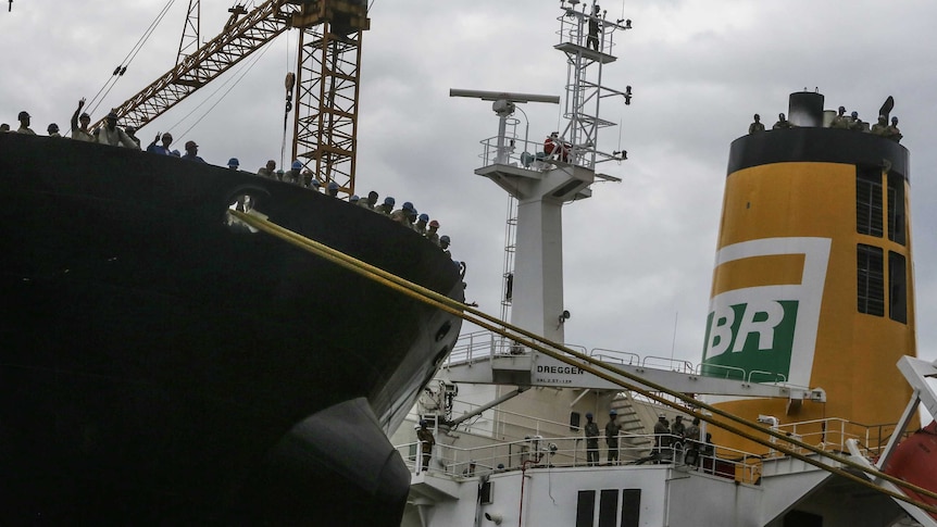 Workers stand on Petrobras oil tankers