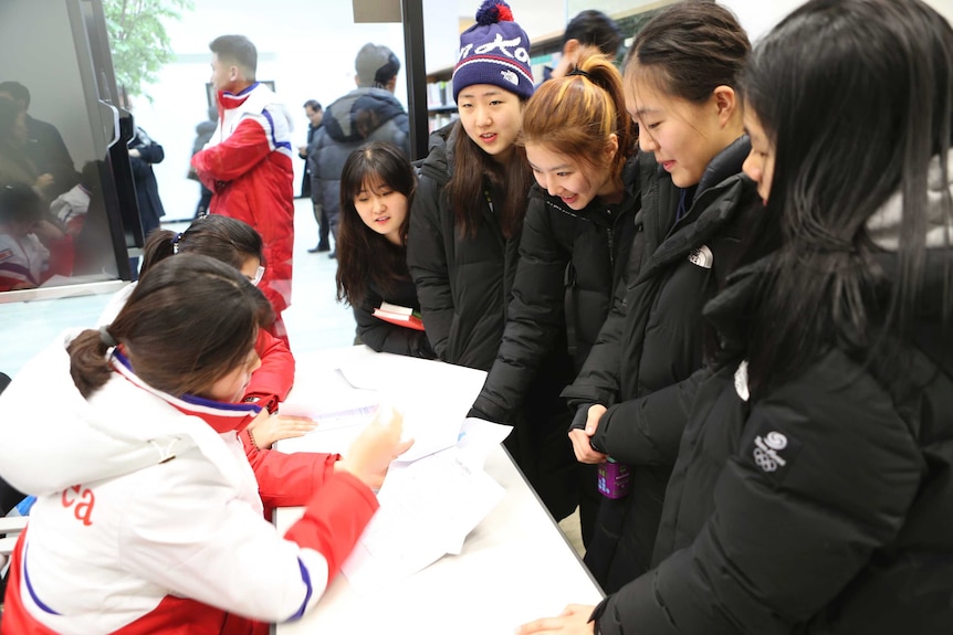 South Korean women's ice hockey players (R), talk to North Korean players (L) on January 25, 2018.