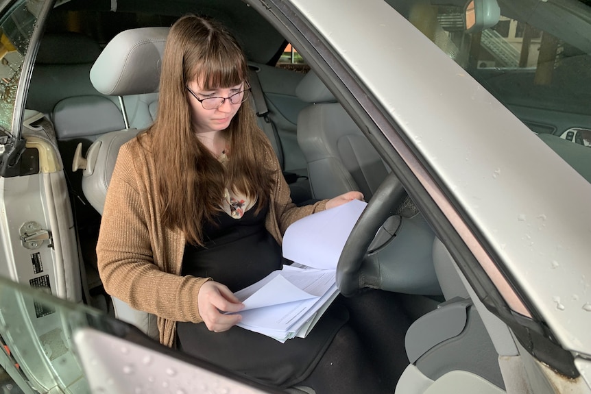 a woman in a car reading documents