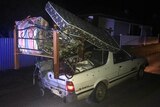 A white ute stacked high with a bed, mattress and other belongs.