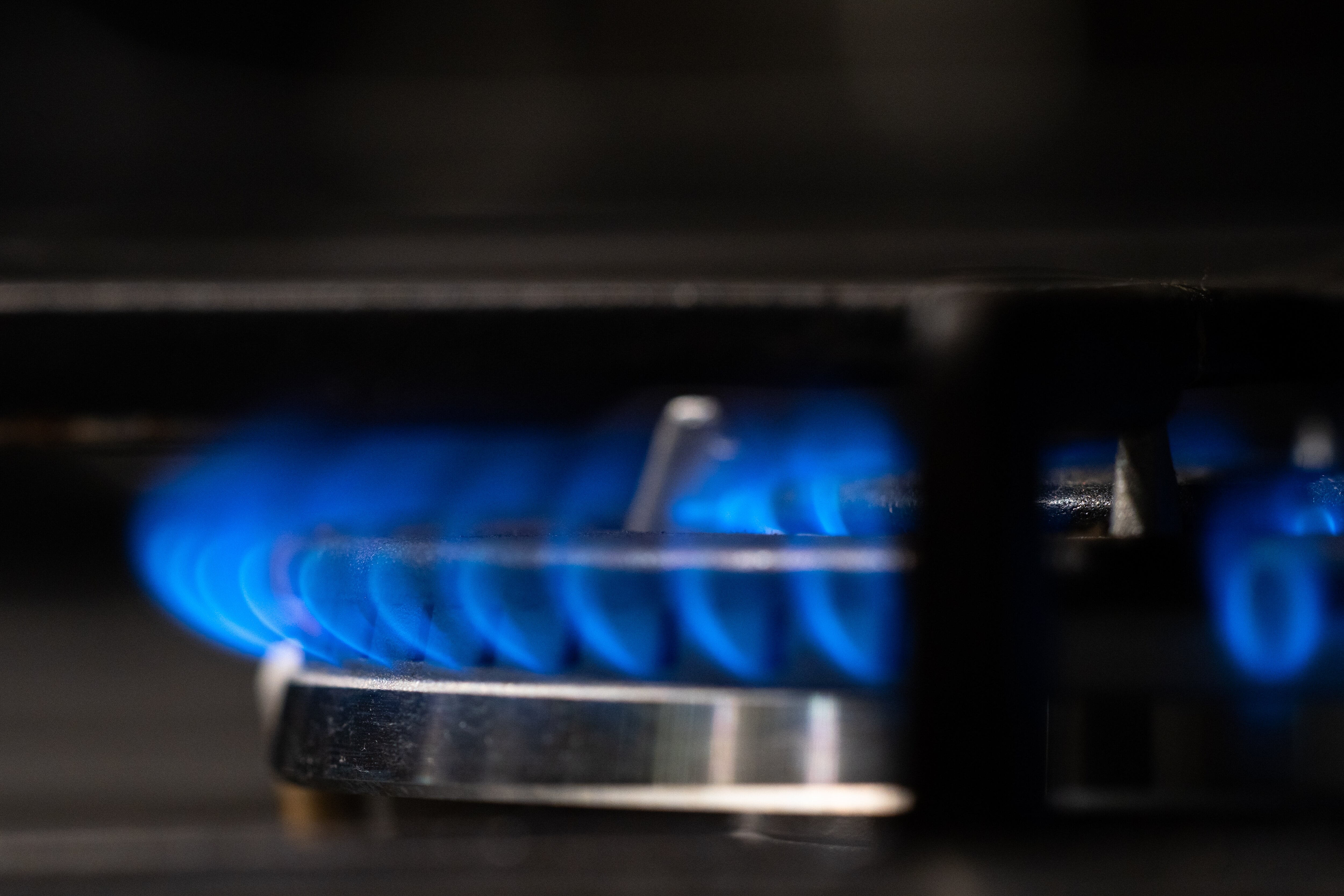 Gas stove top turned on. Blue flames against a dark black background.