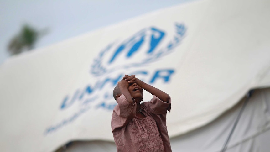 A girl standing in front of a UN shelter for the internally displaced Rohingya in Myanmar.