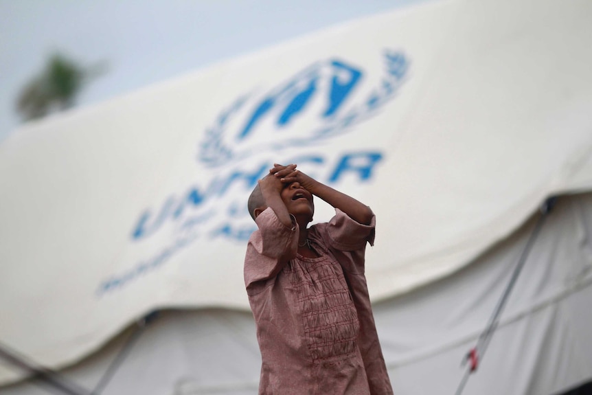 A girl standing in front of a UN shelter for the internally displaced Rohingya in Myanmar.