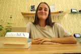 A young woman smiles while leaning on a counter