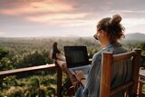 Woman sits on the balcony with her laptop.