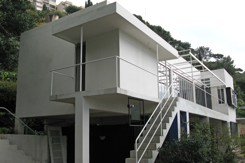An exterior shot of Eileen Gray's E1027 house, a rectangular design elevated off the ground.