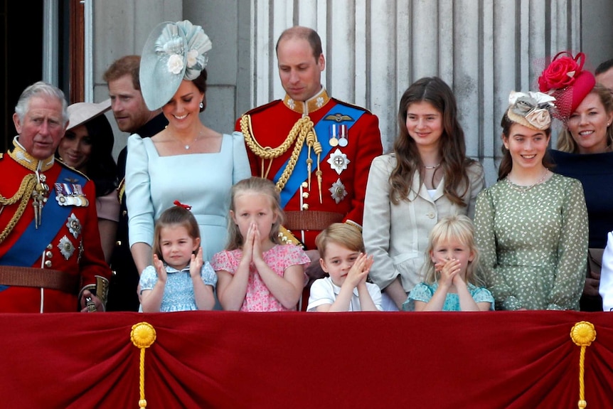 Young royal children watch on in awe from the balcony of buckingham palace during trooping the colour.