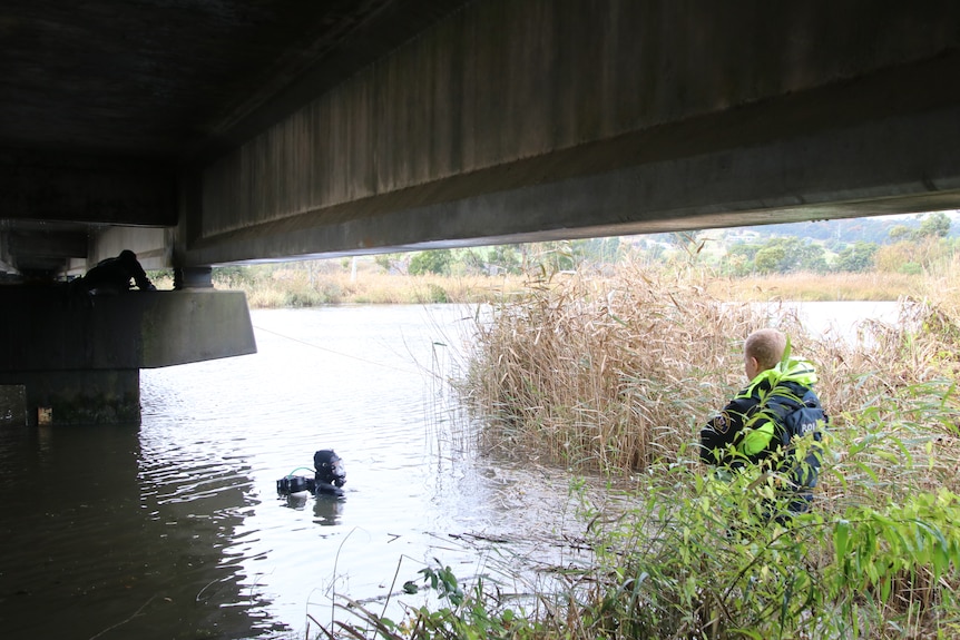 Police divers in a river near a bridge