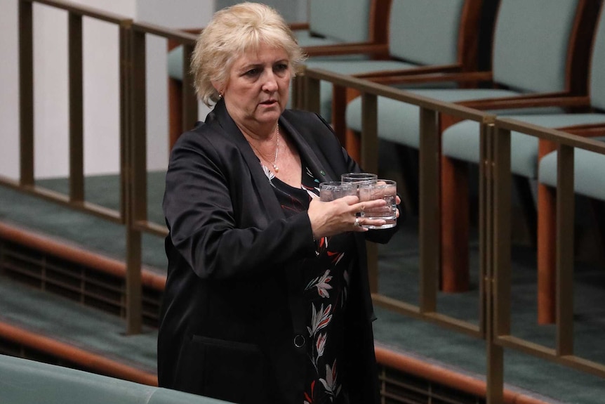 Michelle Landry carries three glasses of water as she walks through the House of Representatives