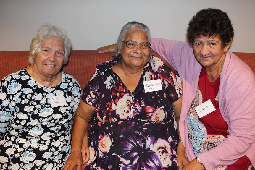 Three women sit on a couch.