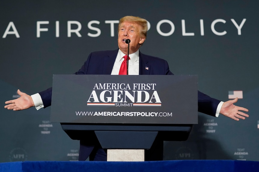 Trump gestures during a speech at a podium.