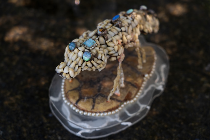 a small sculpture made of teeth and jewelry in the shape of a lizard.