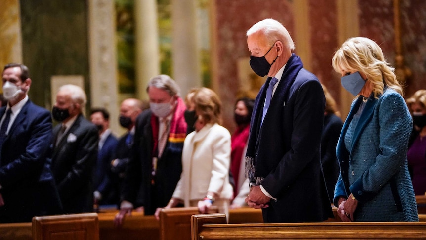 President Joe Biden and Dr Jill Biden, each wearing a face mask and praying.