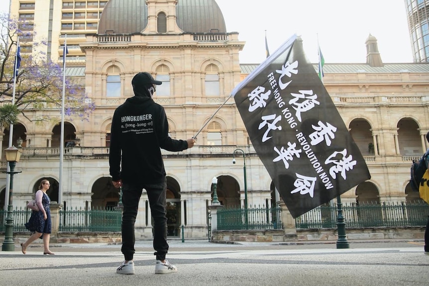 A Hong Kong pro-democracy protester dressed in black holds a black flag.