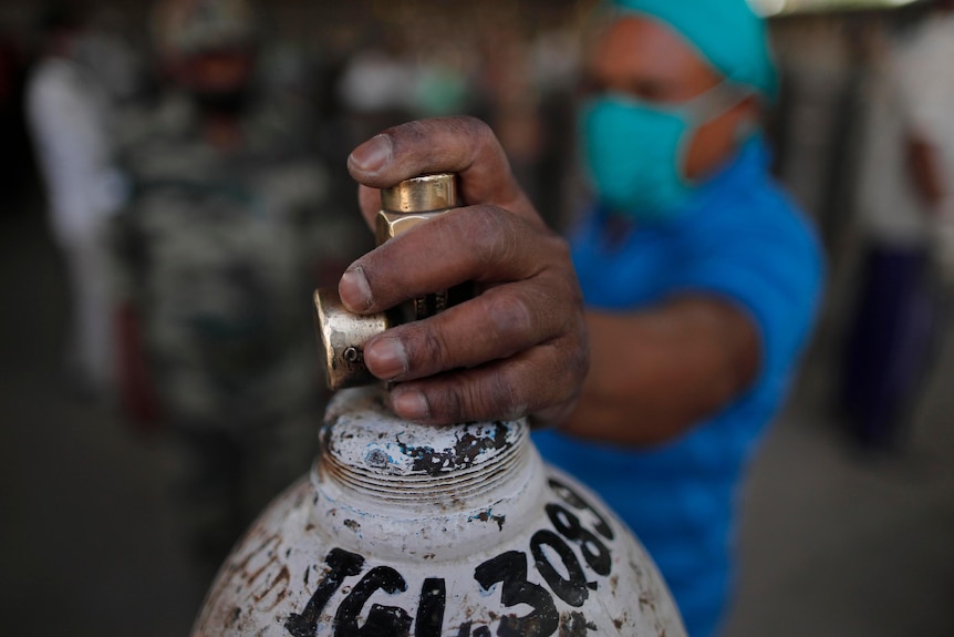 A man waits to refill a medical oxygen cylinder at a charging station on the outskirts of Prayagraj, India.