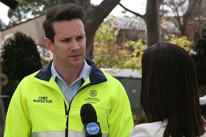 A man wearing a high vis jumper is interviewed by a reporter