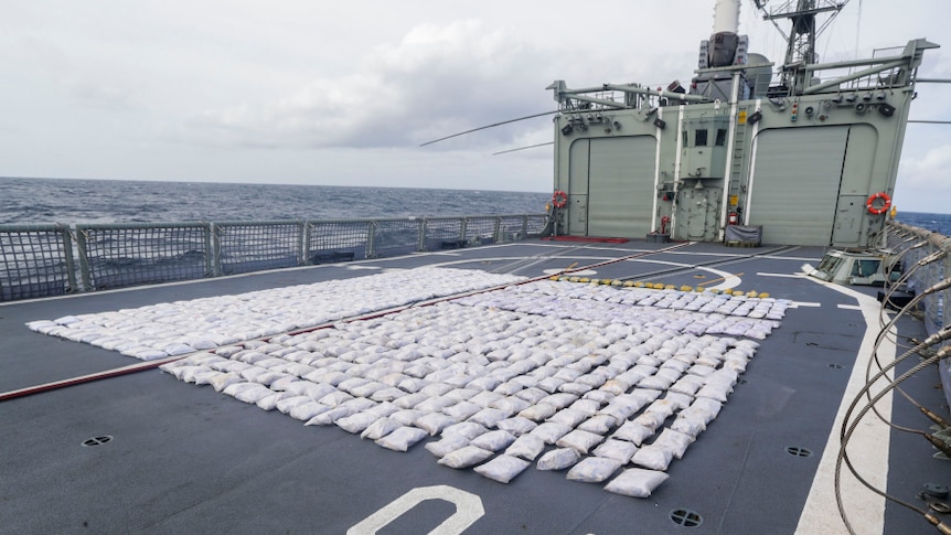 Hundreds of bags of heroin are laid out on the deck of a ship.