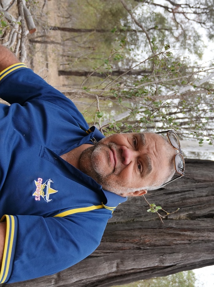 Indigenous man sits in front of a big tree