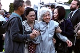 A man and two young women support an older lady wearing a grey jumper on a street in Beechboro.