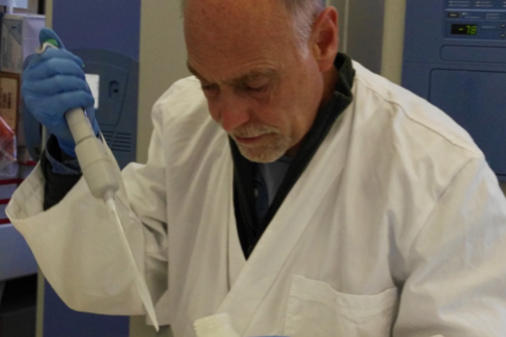 A man in a lab coat with a syringe in a laboratory