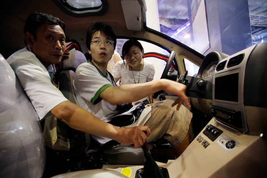 Des gens assis dans une voiture électrique lors d’un salon de l’automobile électrique et propre à Pékin, le 13 juillet 2009. 