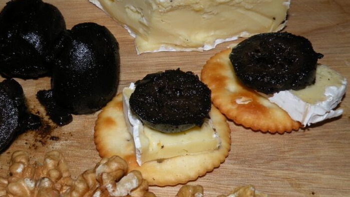 Black pickled walnuts on cheese and crackers