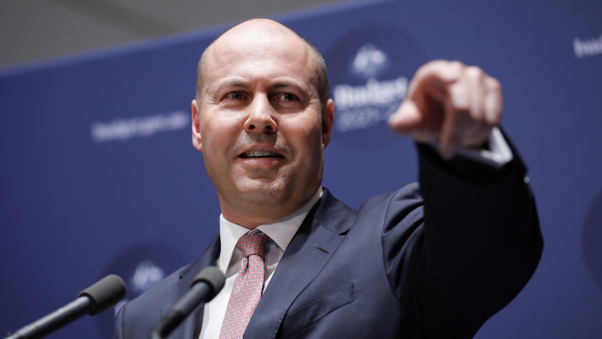 Josh Frydenberg points into the distance while holding a press conference