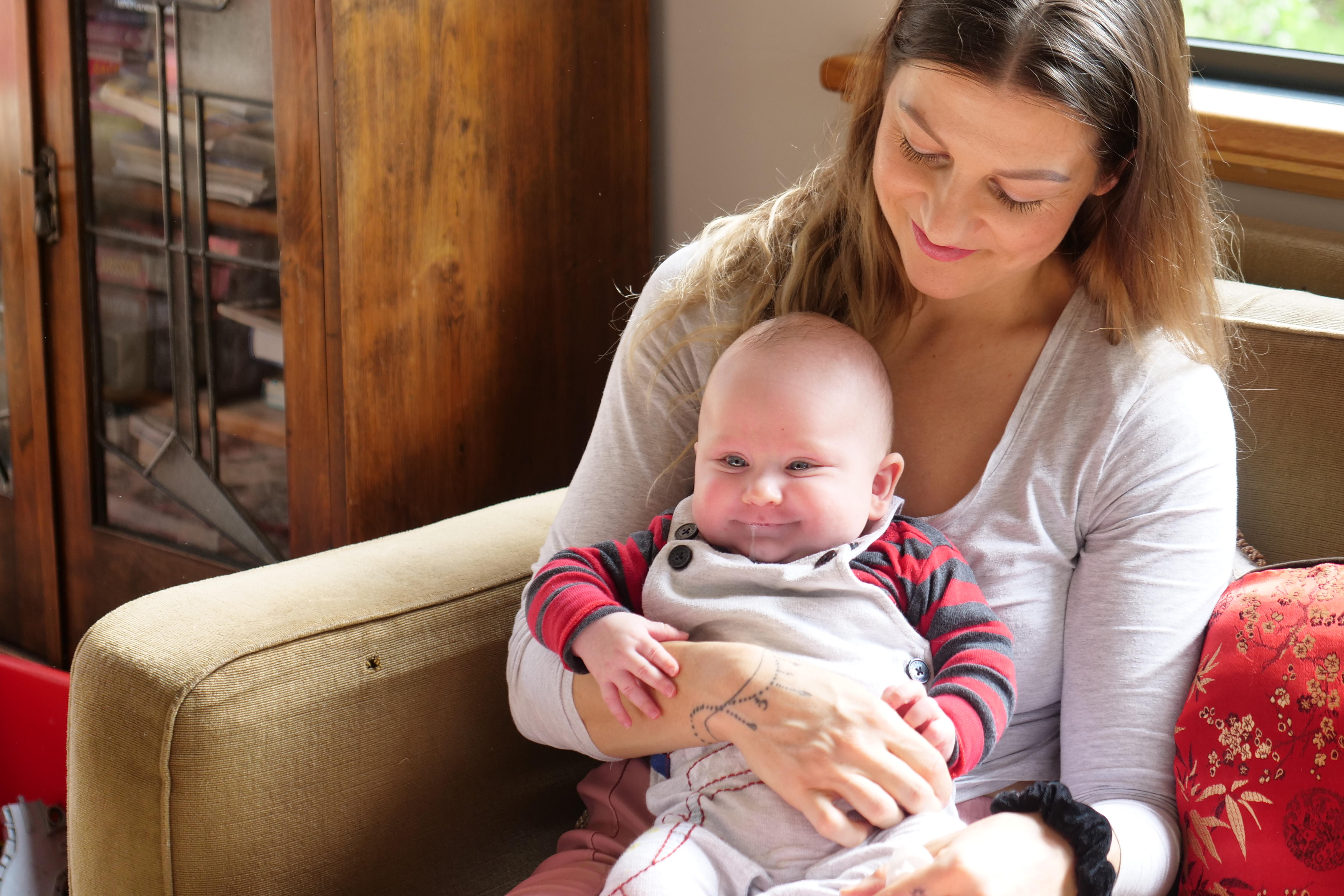 baby (being held by mum) smiles blissfully through a really runny nose situation
