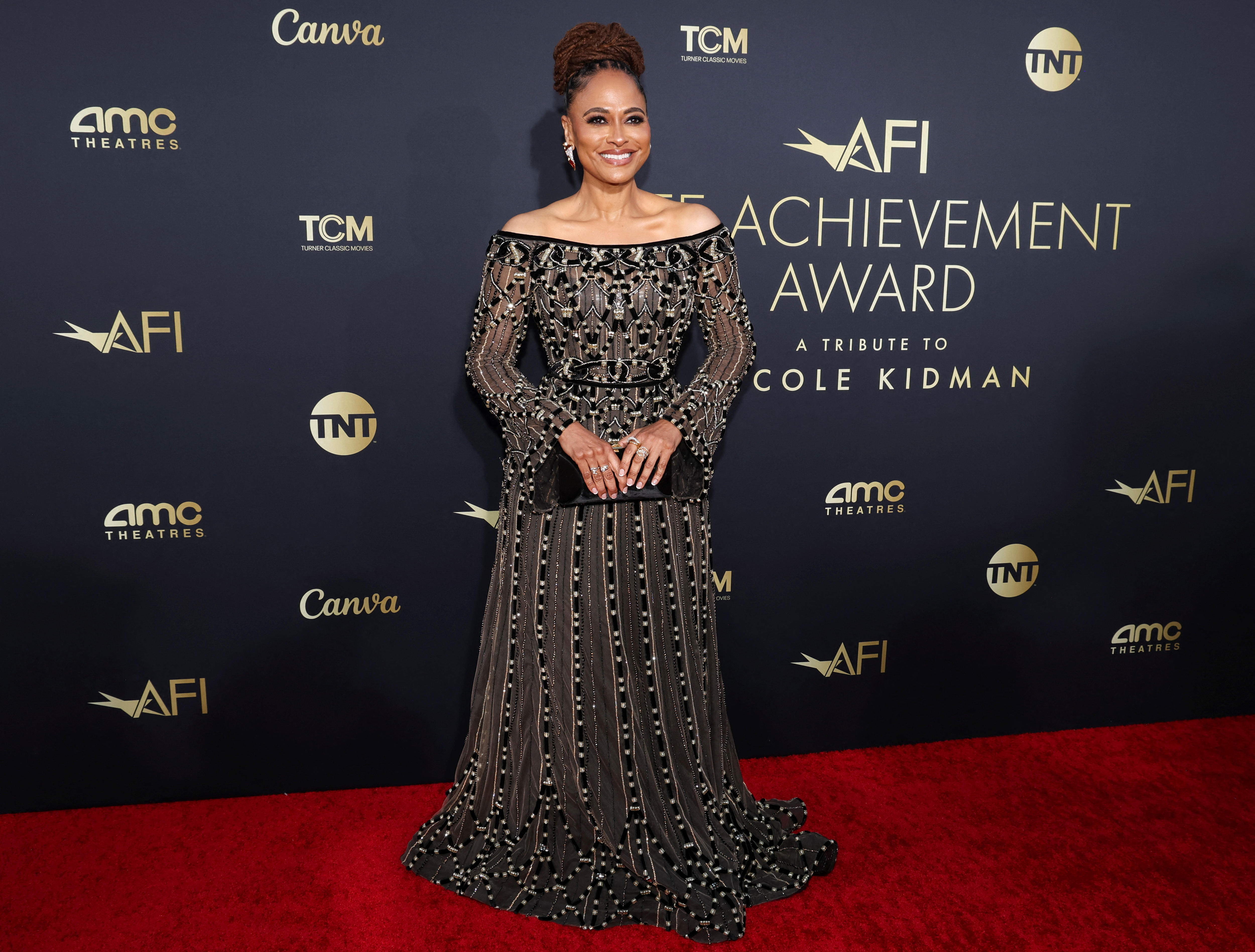 Ava DuVernay wearing a long black lacy gown with long sleeves and an off-the-shoulder neckline