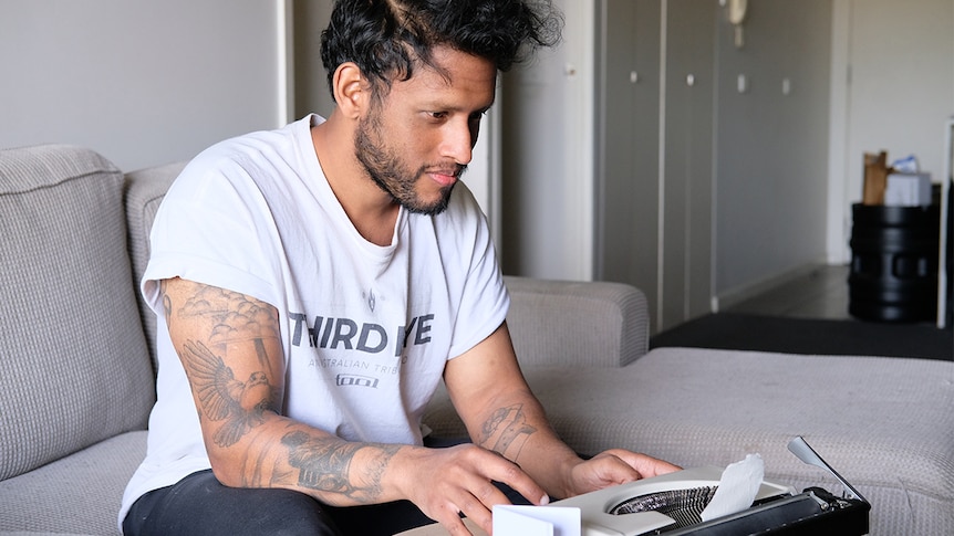 Ricky Kuruppu sitting on a couch typing on a manual typewriter