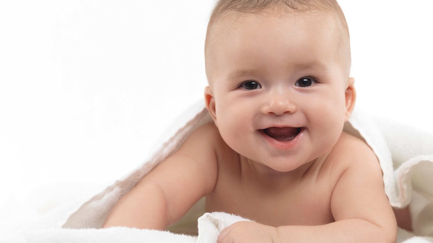 A smiling four month old baby boy looking at the camera.