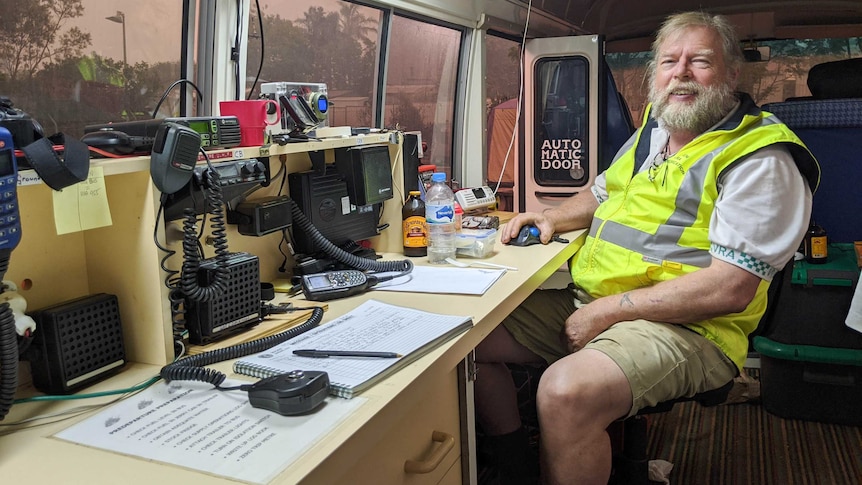 A man sits inside a bus surrounded by radio equipment