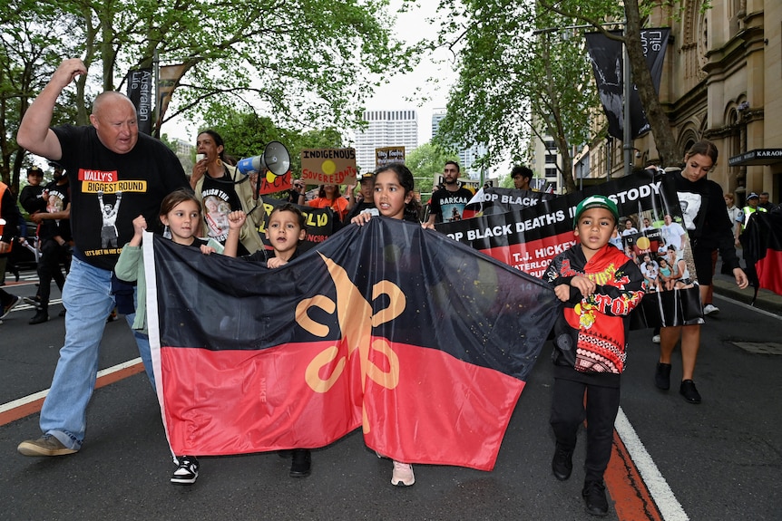 几名原住民儿童举着原住民旗帜