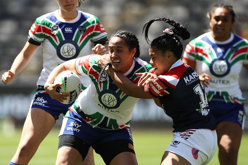 Tazmin Gray tries to fend off a tackle while holding a football.