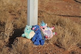 Three stuffed toys at the base of a lamp post