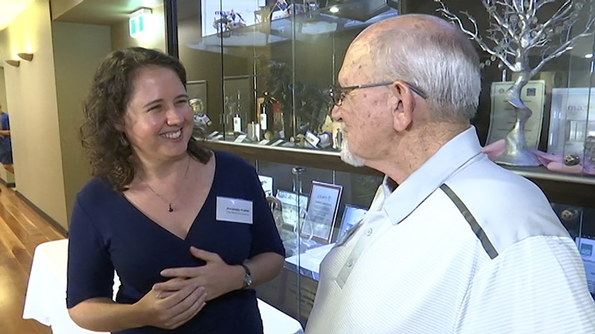 A woman smiling speaking to an older man.