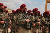 Turkish-backed forces from the Free Syrian Army stand in formation wearing red berets.