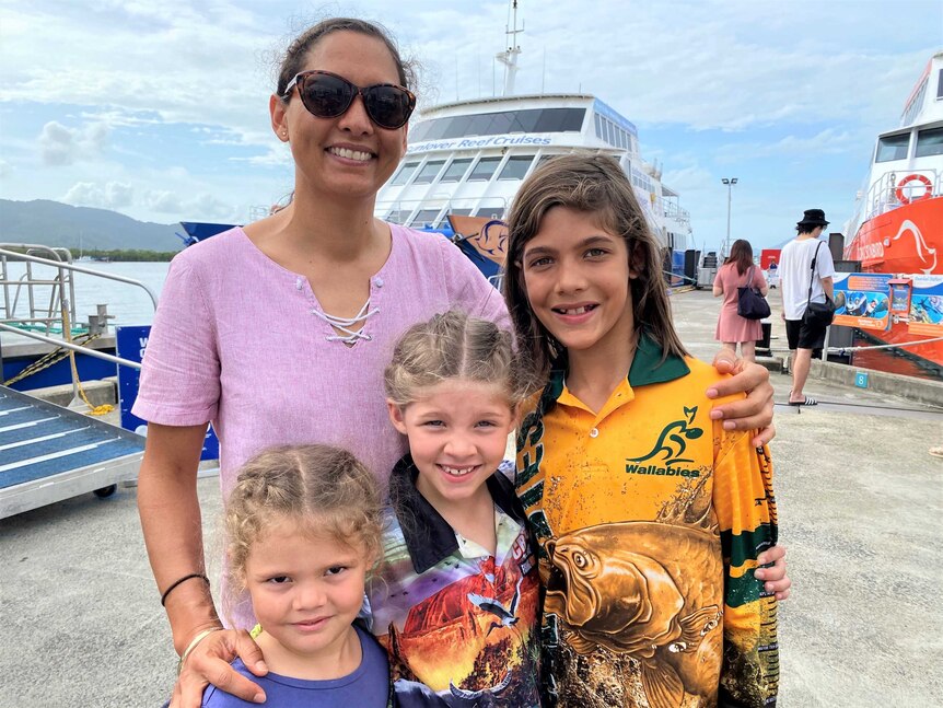 Woman and three children smiling in front of Sunlover Reef Cruises boat