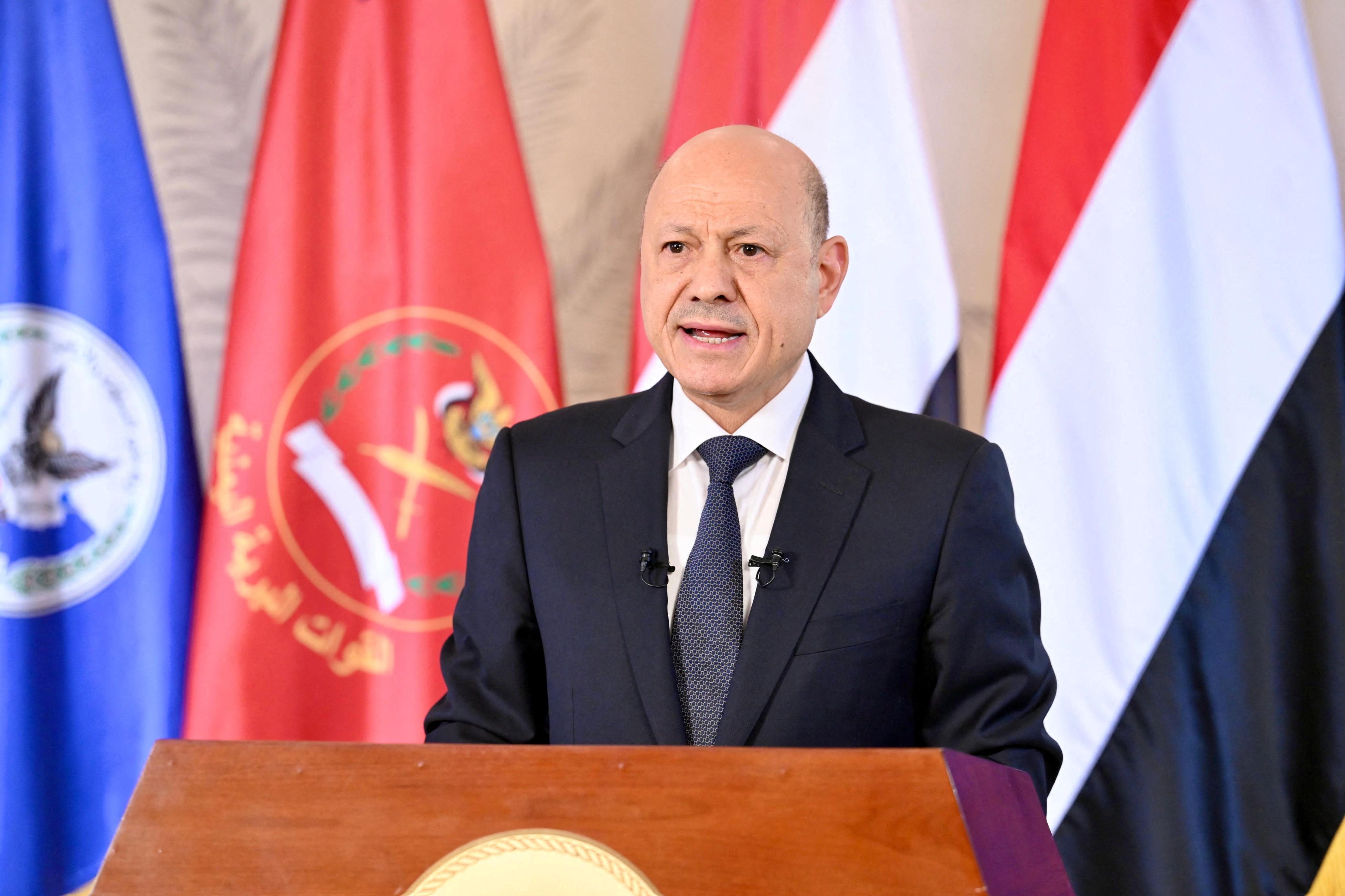 A man in a black suit speaking at a podium