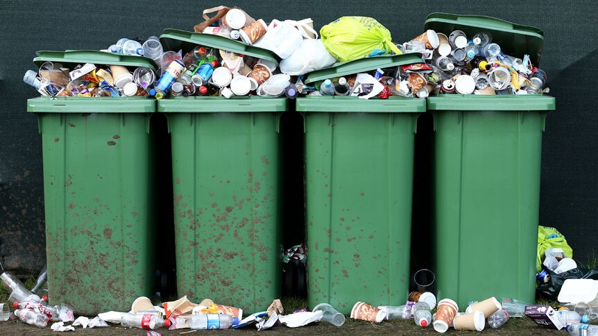 Four wheelie bins overflowing with rubbish