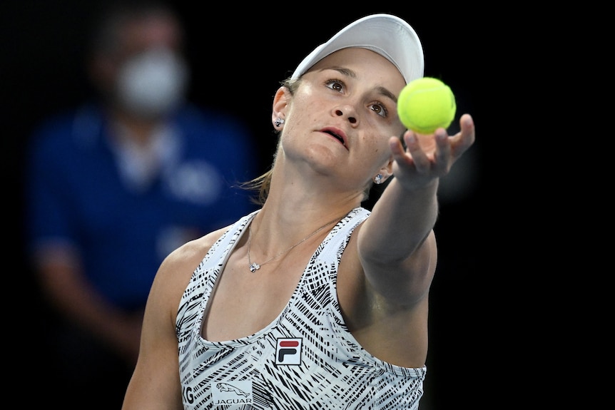 An Australian female tennis player holds a ball as she is about to serve.