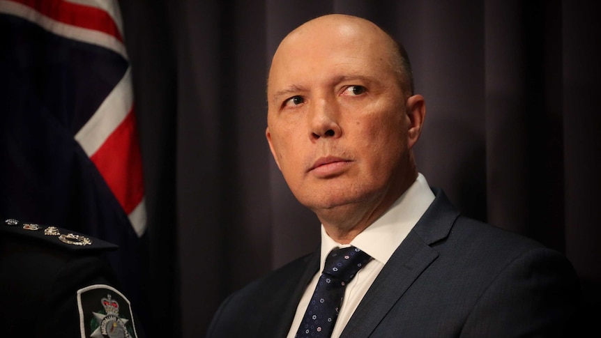 Dutton is wearing a dark suit, his eyes darting to the right of frame.
